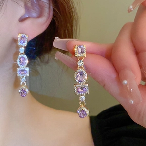 Detail of luxury geometric earrings with purple crystal drops and sparkling diamonds