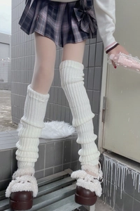 Close-up of white cable knit leg warmers styled with a plaid skirt and fuzzy shoes