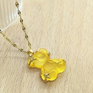 Detail of gold necklace with bear pendant featuring resin finish and zircon star accents