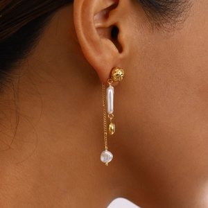 Detail of gold drop earring with natural pearl and bow tassel on model's ear