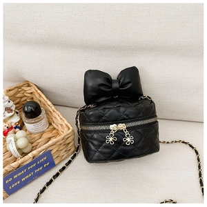 Detail shot of a black quilted mini bag with a large bow and golden flower zipper pull