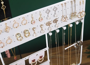 Macro detail of white metal jewelry organizer with earring holes and necklace hooks
