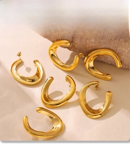 Detailed macro view of six PVD gold-plated U-shaped earrings on a natural wooden display