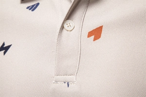 Dettaglio macro del colletto polo in tessuto piqué beige con stampa geometrica