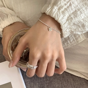 Detailed close-up of a liquid metal texture ring and silver chain bracelet with smile pendant