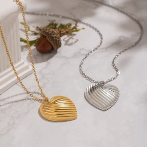 French style textured heart necklaces in gold and silver finish on marble surface