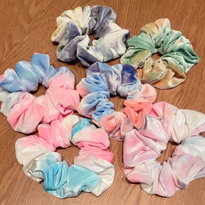 Set of six colorful tie-dye velvet hair scrunchies in soft macaron tones on wood
