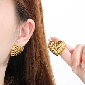Quilted gold heart earrings in 18k stainless steel shown on model and held by hand