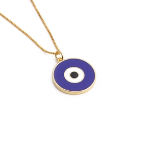 Macro view of a circular gold evil eye pendant necklace with blue and white enamel detail