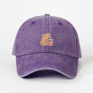 Detailed close-up of a purple washed denim baseball cap with a cute capybara embroidery