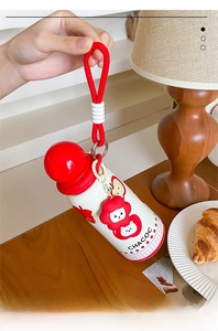 Detail of cute cartoon vacuum flask with red ball cap and woven carrying rope