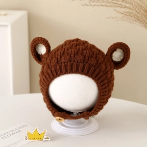Detail of a brown knit baby hat with bear ears and wood buttons for winter warmth