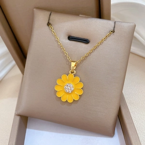 Detailed macro view of gold-tone daisy pendant with yellow enamel and sparkling rhinestones