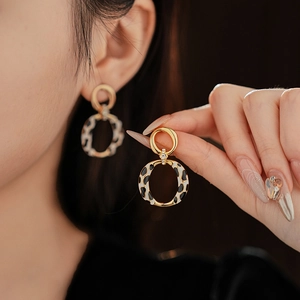 Close-up of leopard print hoop earrings with crystals on a vintage gold metal finish