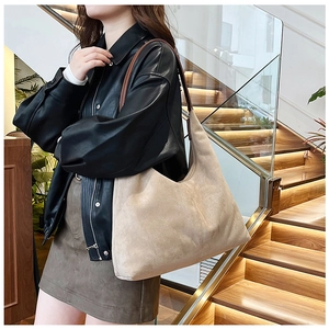 Model wearing large beige suede tote bag showing its slouchy minimalist silhouette