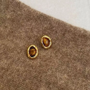 Detailed close-up of vintage gold earrings with tiger eye stone on brown knit fabric