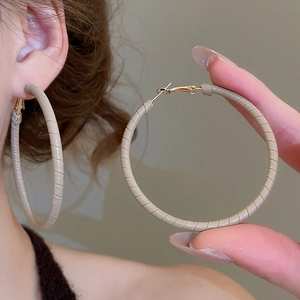 Detailed view of large hoop earrings wrapped in beige textured leather for women
