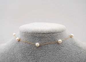 Detail of elegant gold chain necklace with freshwater pearls on a mannequin bust