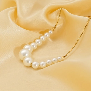 Detail showing gradient pearls and gold metal chain on a soft silk backdrop