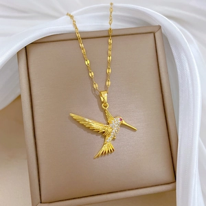 Gold woodpecker pendant necklace with crystals on beige jewelry box with white silk