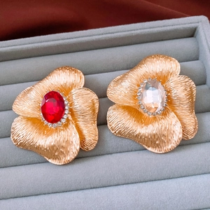 Detail of vintage flower brooch featuring gold brushed metal and large red oval gemstone