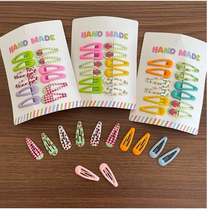 Detailed flat lay of colorful mini BB hair clips with fruit and floral patterns on wood