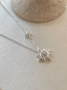 Macro shot of a 925 silver star necklace with zircon sunburst pendant on stone