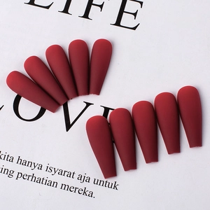 Close-up of matte burgundy coffin press-on nails arranged on a stylish white magazine