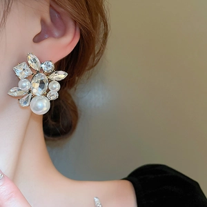 Detail of elegant gold earrings with clustered rhinestones and imitation pearls on model