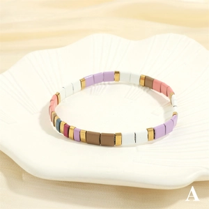 Detail view of colorful enamel Tila beads with golden accents on a shell tray