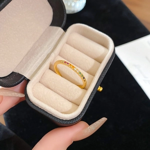 Detail of a thin gold ring with rainbow colored zircons presented in a gift jewelry box