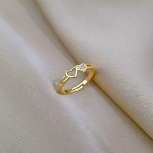 Macro detail of gold adjustable double heart ring with sparkling zircon on silk