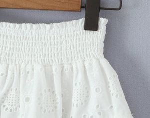 Detail van witte elastische tailleband met verfijnd geborduurd ajourpatroon op de rok