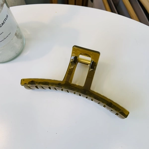 Detailed top view of large olive green hollow claw clip with golden metal spring