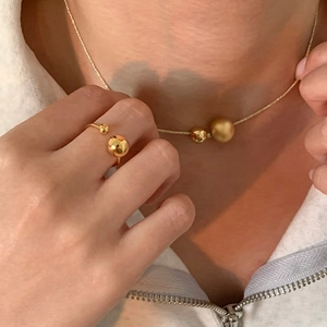 Detail of elegant minimalist gold beaded necklace and open ring set on a model