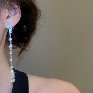 Detail of silver tassel drop earrings with sparkling round cubic zirconia on a model