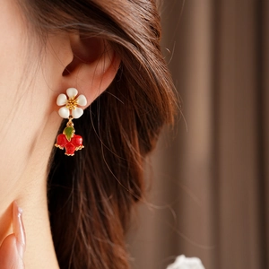 Detail showing vintage white flower and red berry pendant earring on model