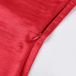 Detail view of high-quality invisible zipper on the elegant red satin dress fabric