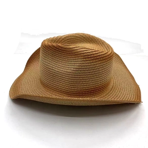 Close-up of a brown wide-brimmed straw sun hat with woven texture and a western style crown