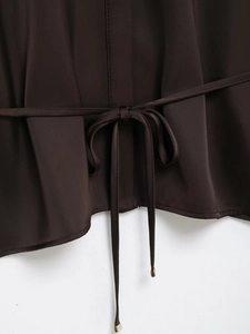 Detail of satin shirt showing back waist tie with golden metal tips and twill texture