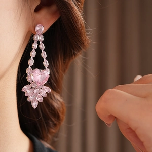 Gros plan détaillé des boucles d'oreilles cœur rose avec des accents de zircon floral