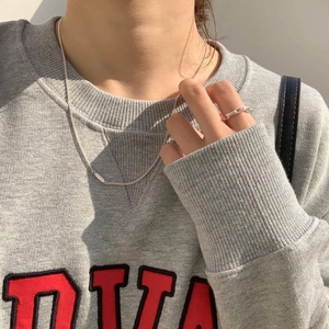 Detailed view of 925 sterling silver knot ring and chain necklace on model