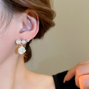 Élégantes boucles d'oreilles fleur en or avec perles et diamants portées par un mannequin