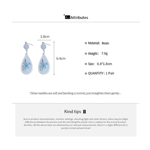 Detail view of light blue resin drop earrings with cyan floral design and dimensions