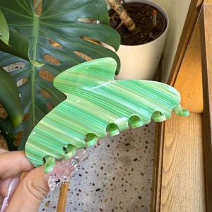 Detail of green and white striped acetate hair claw clip for thick hair styling