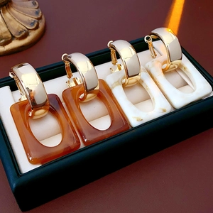 Detailed shot of C-shaped geometric earrings with amber and cream acrylic resin accents