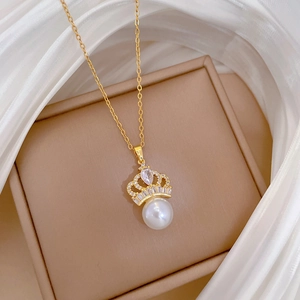 Close-up of gold titanium crown pendant with pearls and crystals on silk background