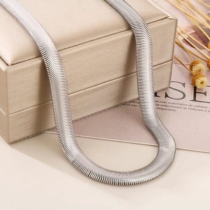 Polished silver flat snake bone chain necklace displayed on a luxury gold jewelry box