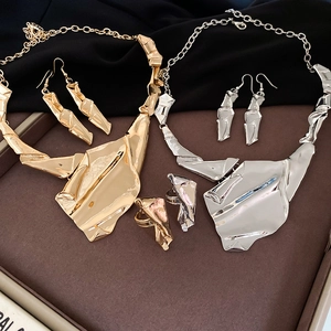 Detailed view of irregular geometric crumpled gold and silver necklace and earring sets