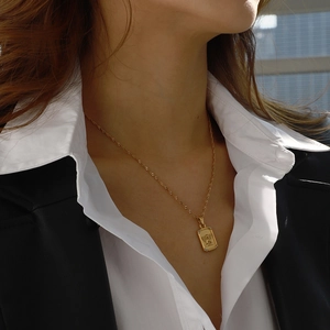 Golden titanium steel angel relief pendant necklace worn on neck over white shirt